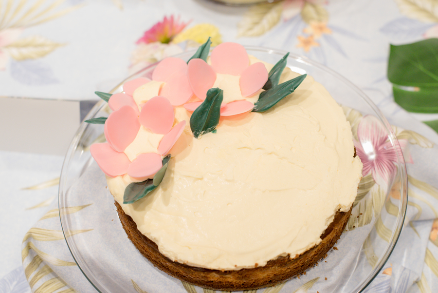 Cake with white frosting, pink flowers and green leaves