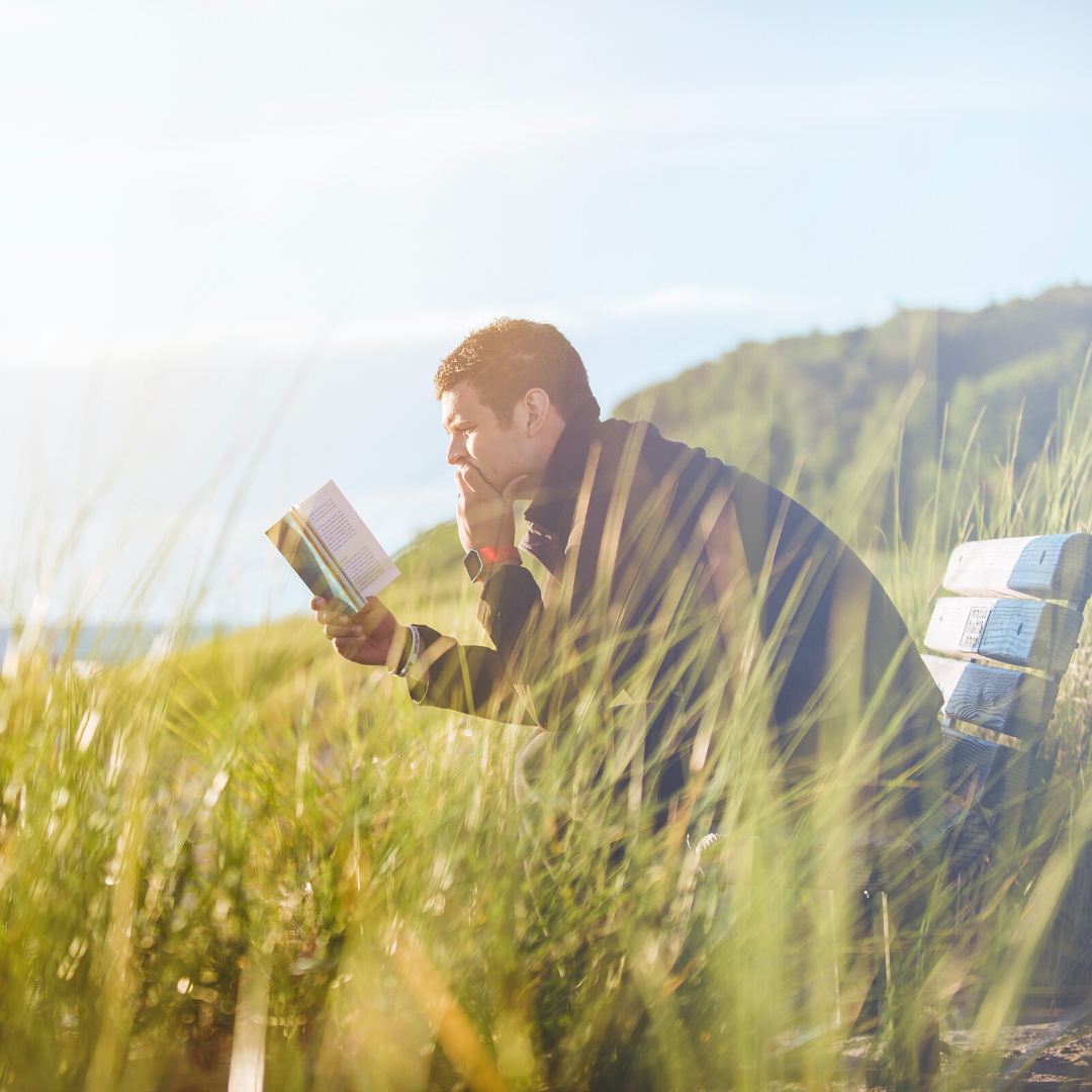 Man Sitting On A Bench Reading A Book